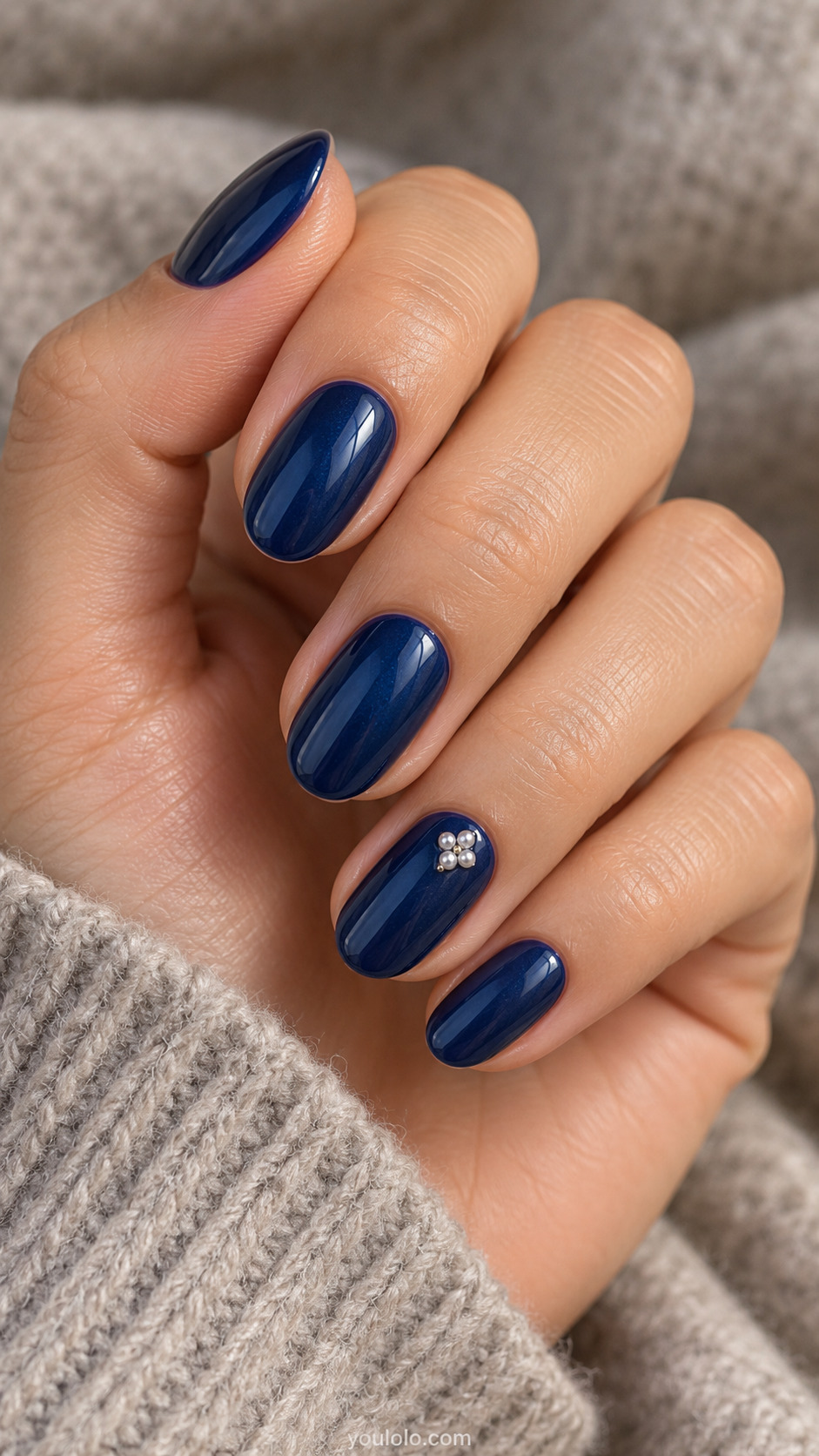 Sapphire with a Tiny Pearl Diamond on a softly gathered feminine hand with detailed sapphire blue manicure