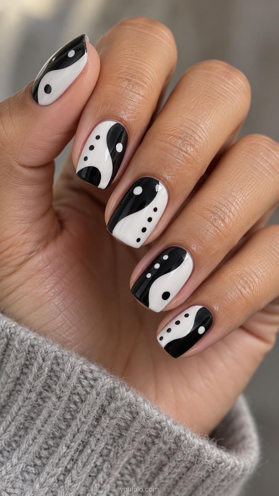 Squoval nails with flowing black-and-white color blocks and sparse contrasting dots