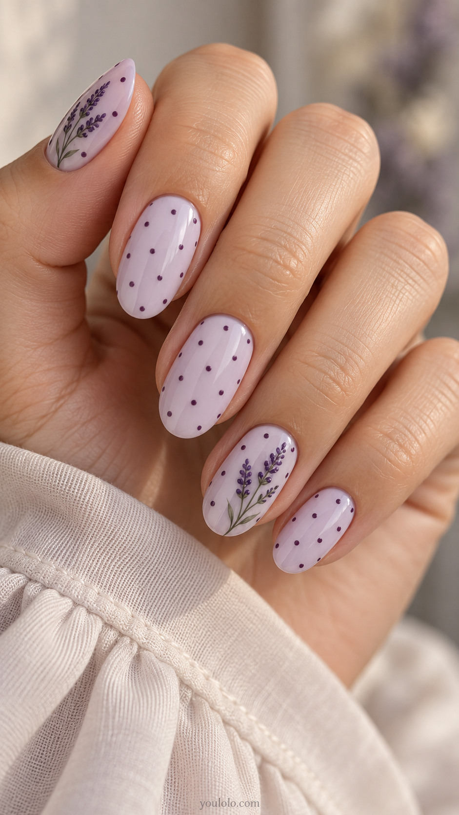 Milky lavender oval nails with plum dots and painted lavender sprigs.