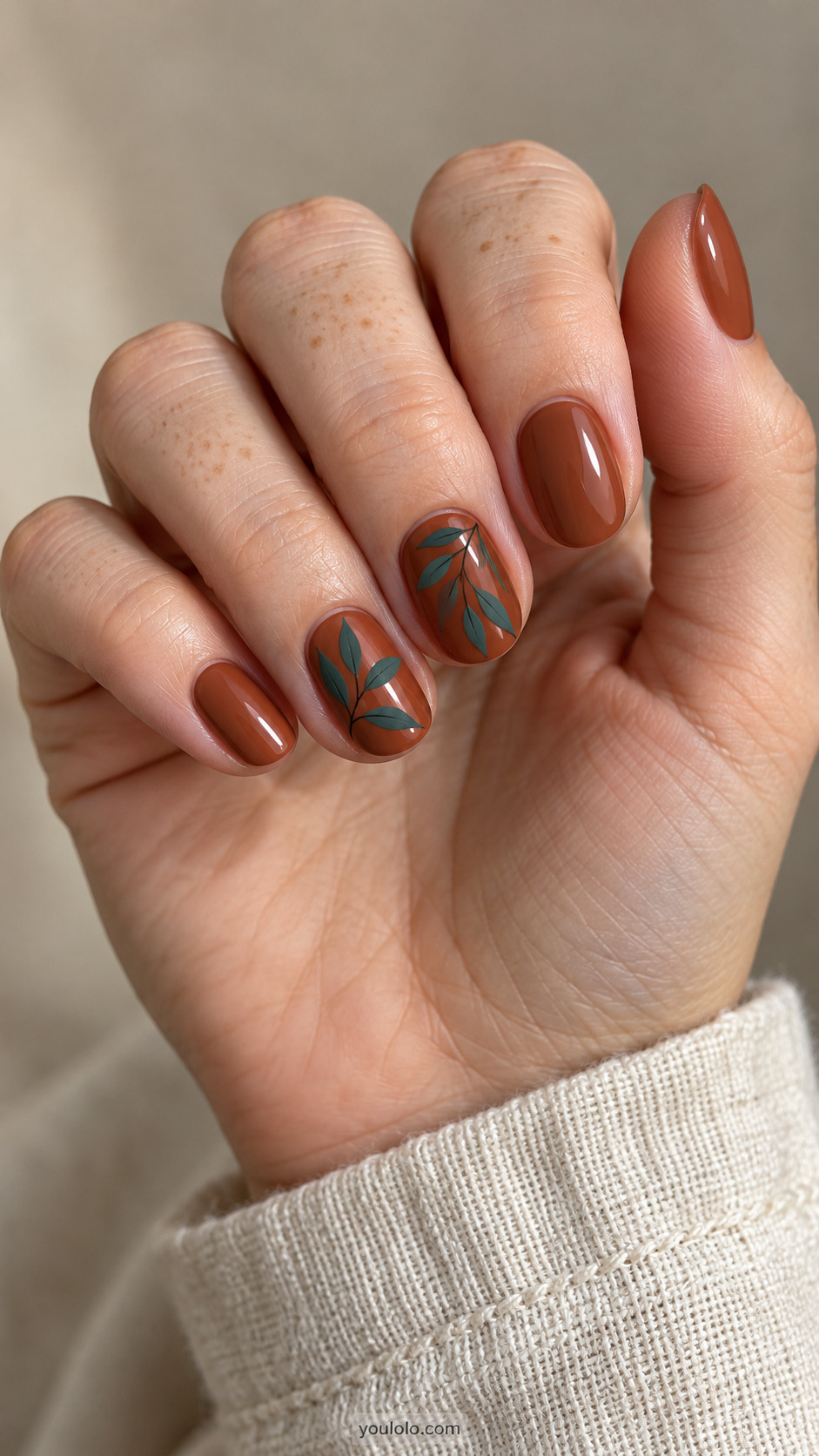Short oval nails with warm cinnamon nails with flat dusty teal narrow willow leaves in loose paired angles on middle and ring nails, slender dark stems; others plain cinnamon.