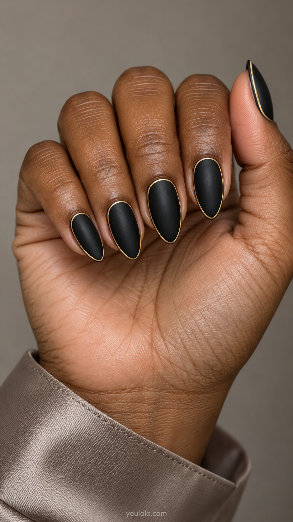 Matte-black almond nails framed by a very thin gold perimeter line