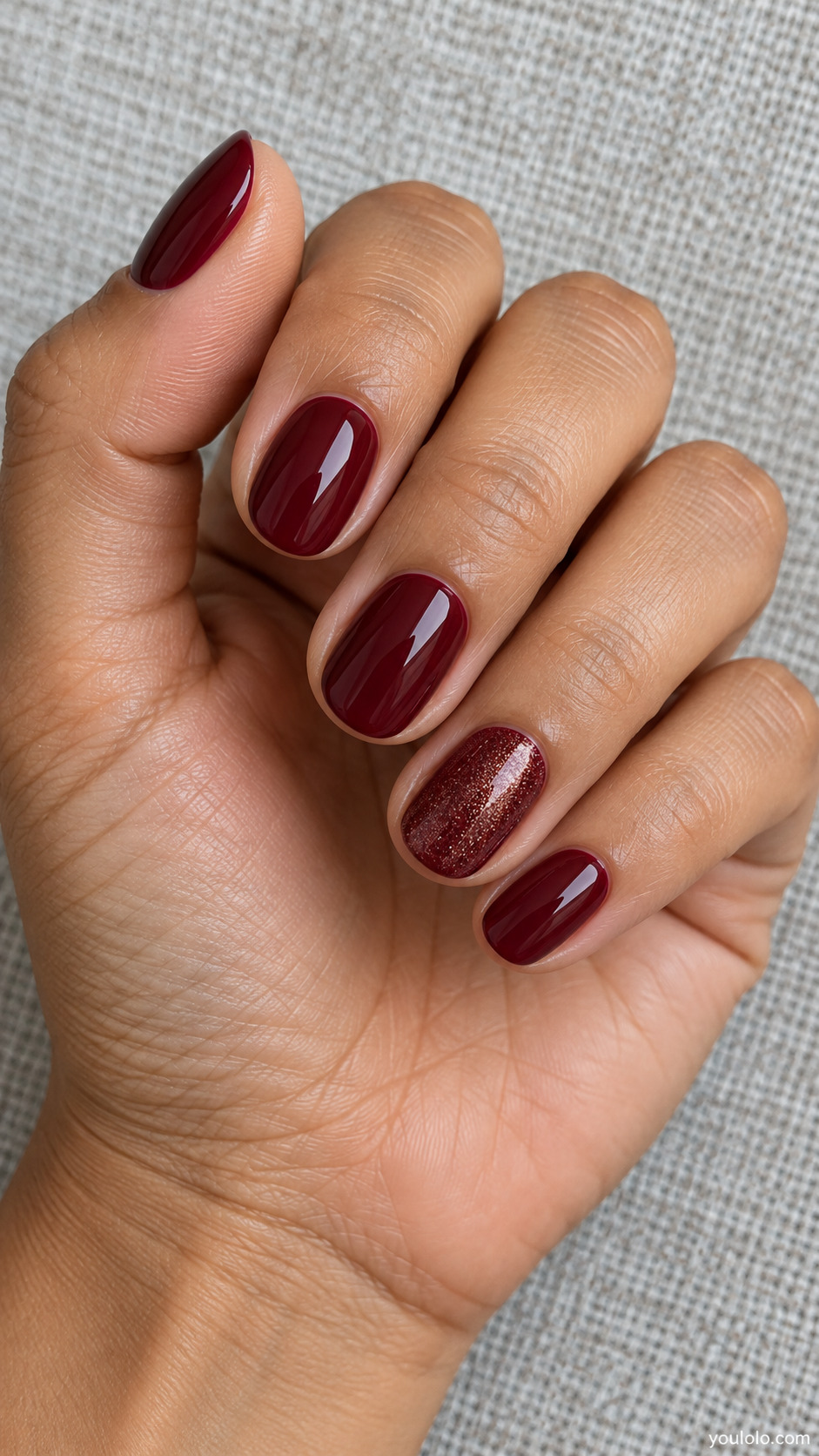 Short burgundy oval nails with fine shimmer on one accent nail