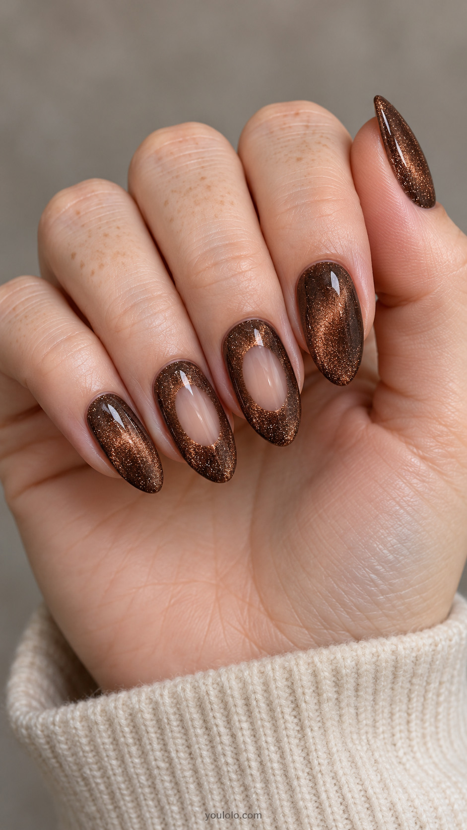 Medium almond nails: brown magnetic velvet nails; ring and middle each have small sheer nude oval window in center enclosed by magnetic brown, clean edges no metallic frame.