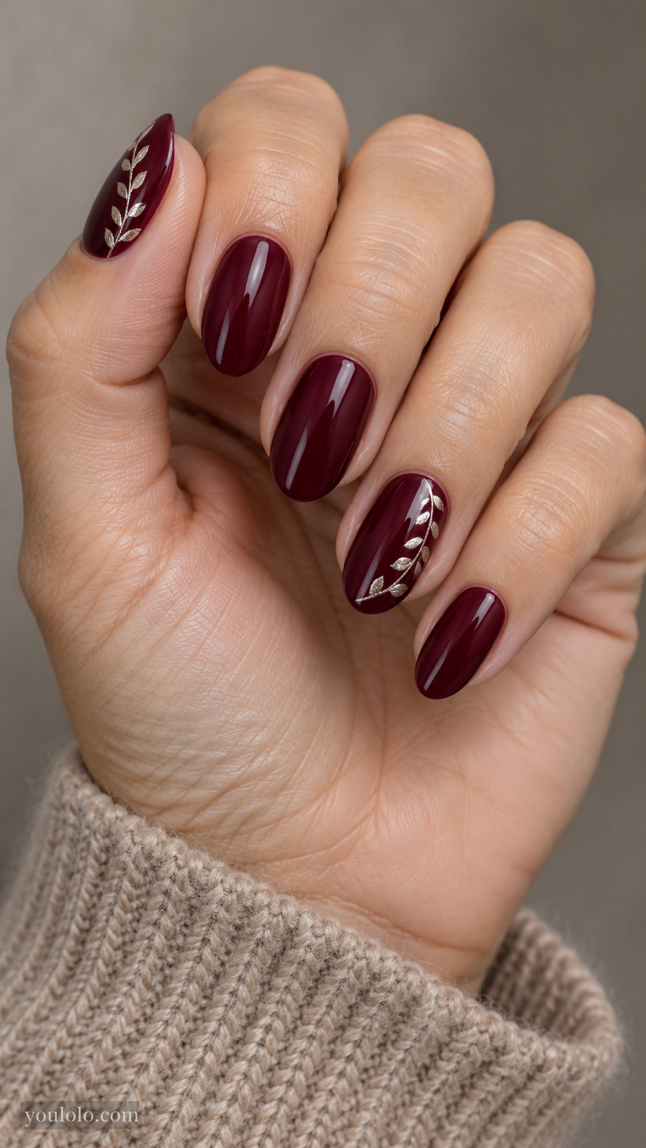 Medium almond nails with deep wine glossy nails with tiny flat antique silver leaf shapes forming a crescent along one side of ring and thumb; other fingers wine plain.