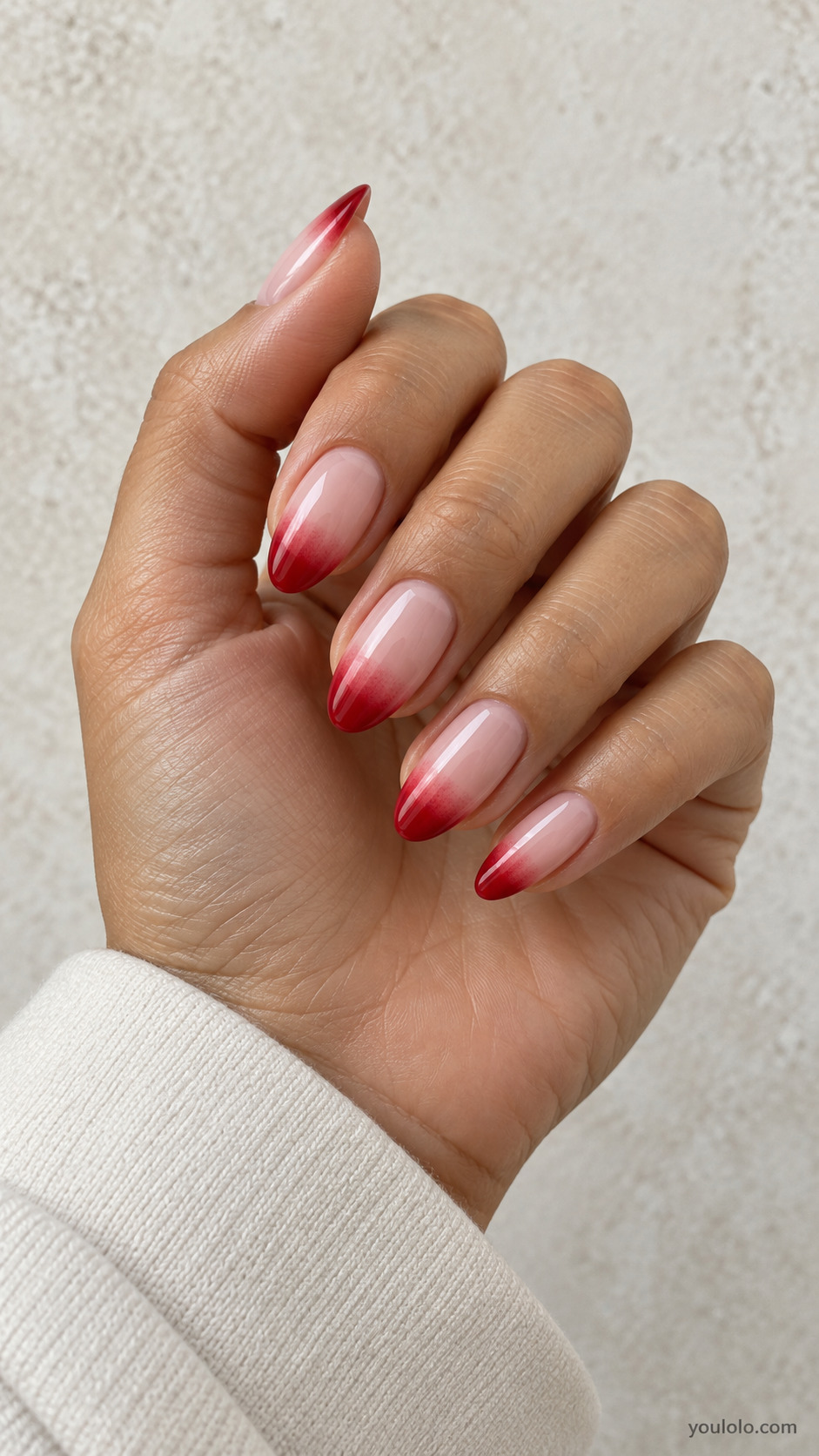 medium almond pale pink nails, red at free-edge softly feathering a short distance into nude, recognizably French gradient on a naturally gathered hand