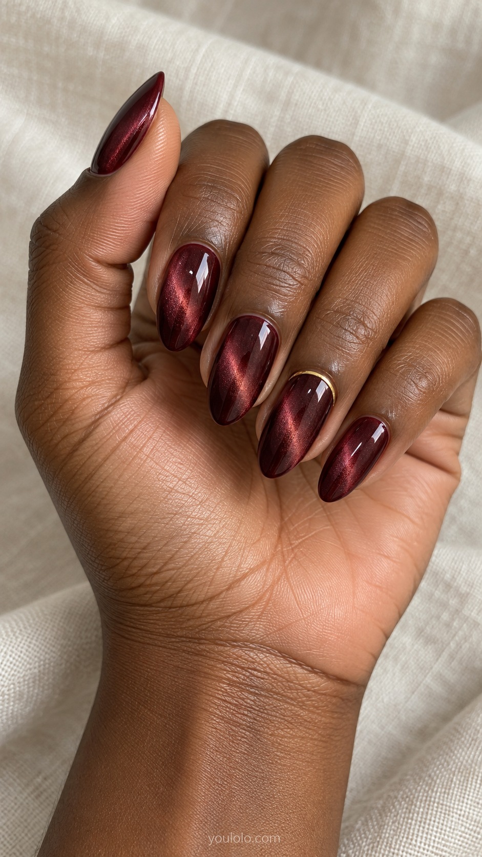 Merlot with a Fine Gold Arc cat eye nails — Medium almond dark merlot magnetic nails with thin gold curved arc near cuticle of ring nail only.