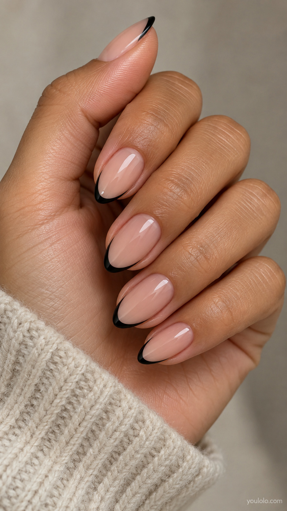 Medium almond nails with sheer nude bases and fine black French tips.