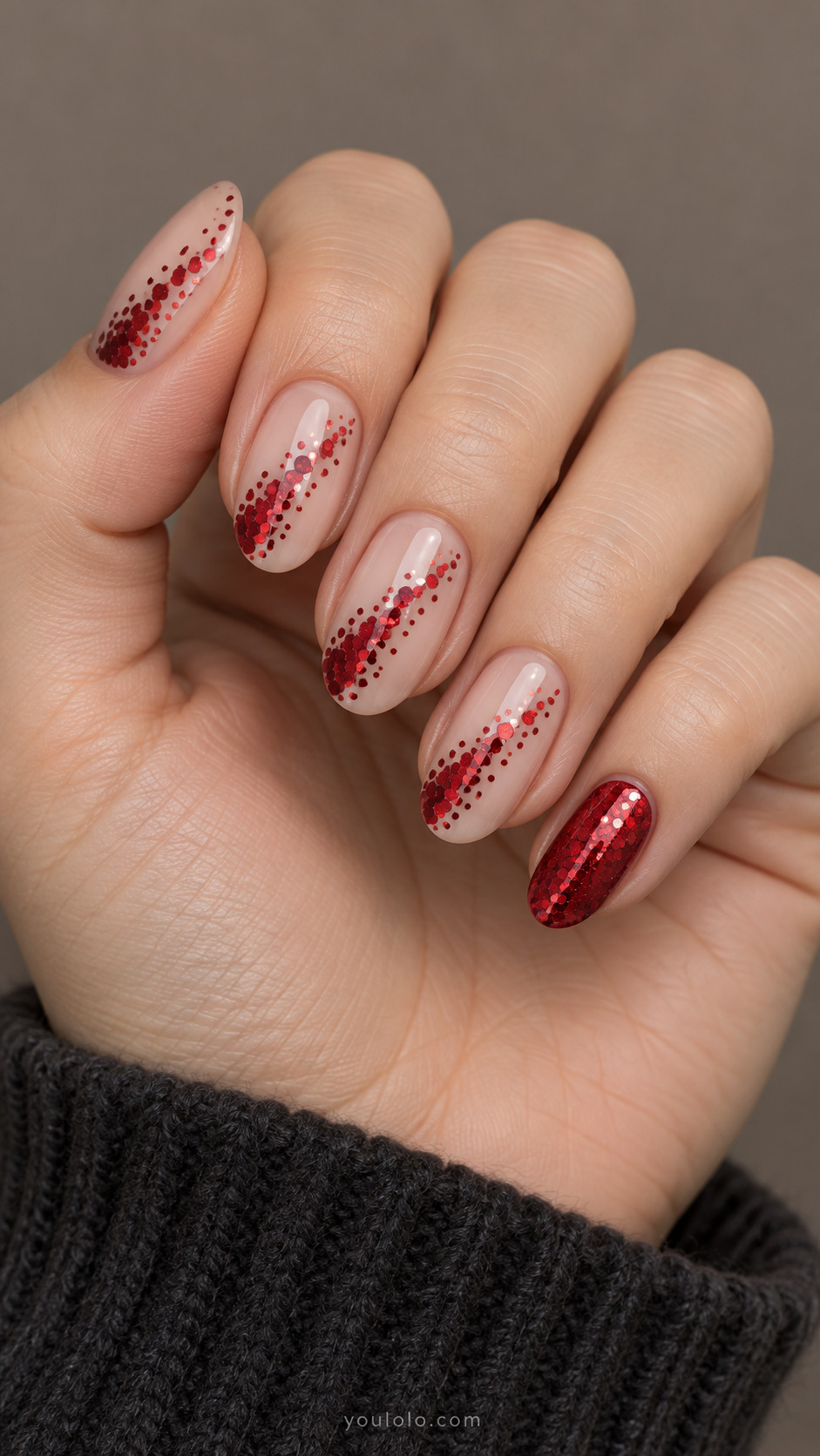 Nude oval nails with diagonal trails of red hexagonal glitter