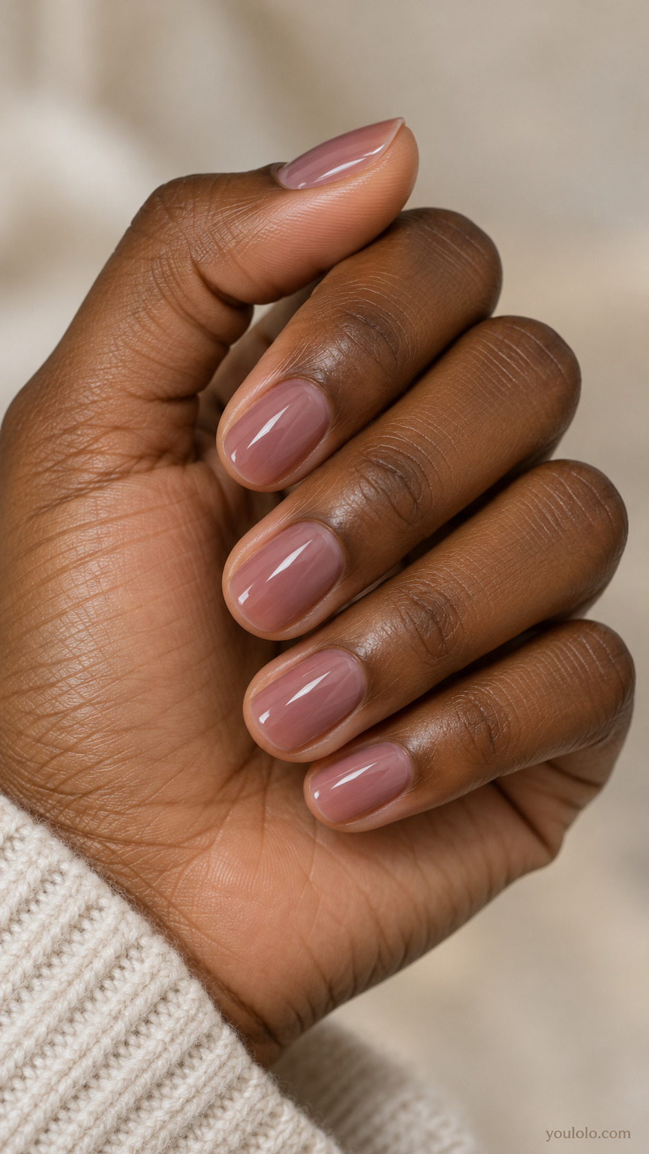 Short round nails with translucent muted mauve rose polish and a soft gloss.